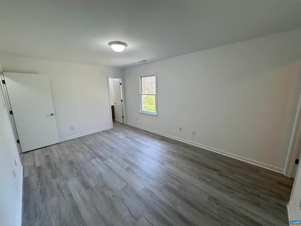 an empty room with wooden floor and window