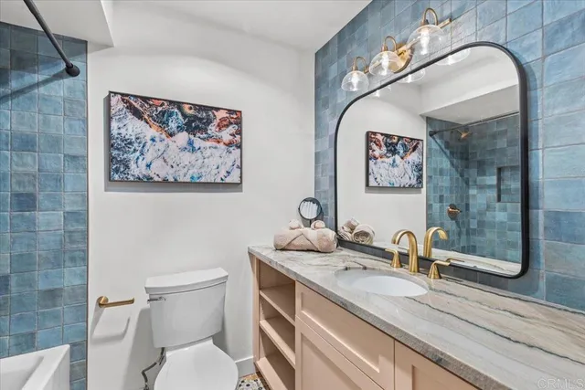 a bathroom with a granite countertop sink mirror vanity and toilet