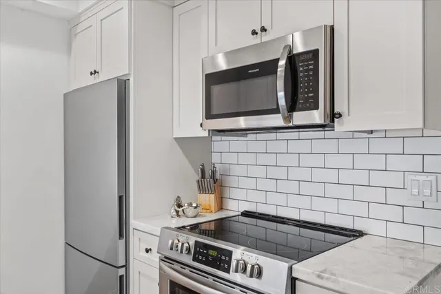a kitchen with granite countertop white cabinets and stainless steel appliances