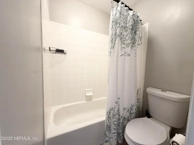 a white toilet sitting next to a bath tub and shower