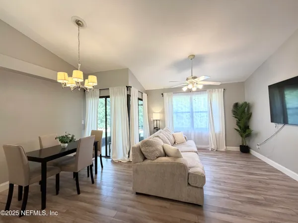 a living room with furniture a chandelier and a flat screen tv
