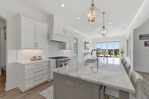 a large white kitchen with a sink and dishwasher a refrigerator with white cabinets