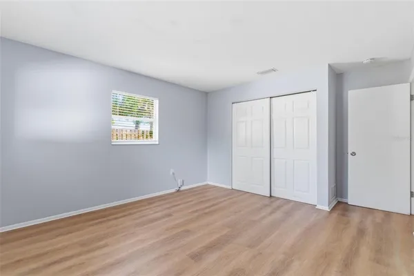 a view of empty room with wooden floor and fan