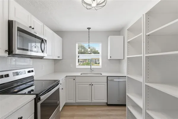 a kitchen with white cabinets stainless steel appliances and a window