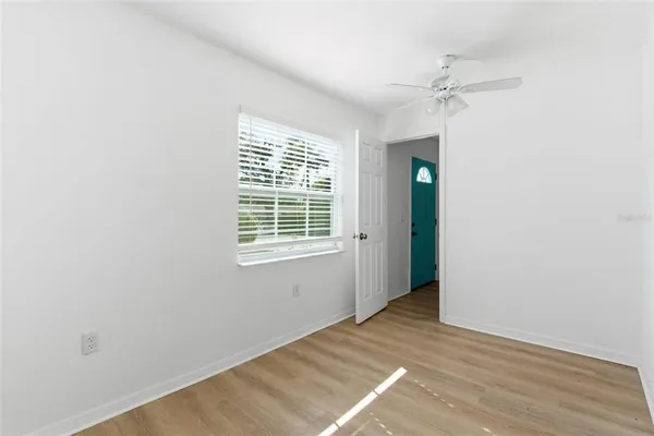 an empty room with wooden floor closet and windows