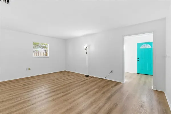 a view of an empty room with wooden floor and a window