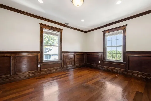 an empty room with wooden floor and windows