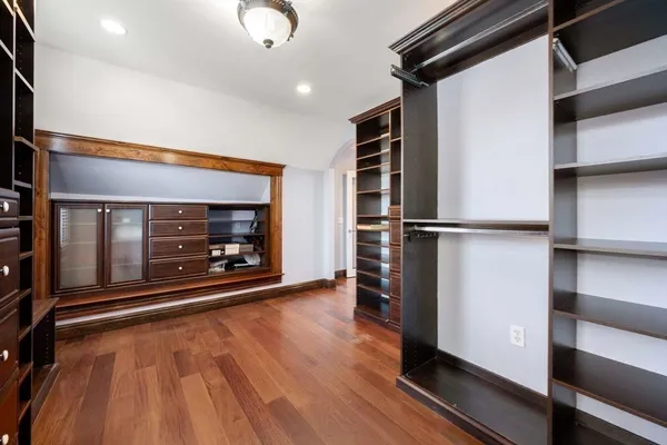 a view of an empty room with wooden floor fireplace and a window