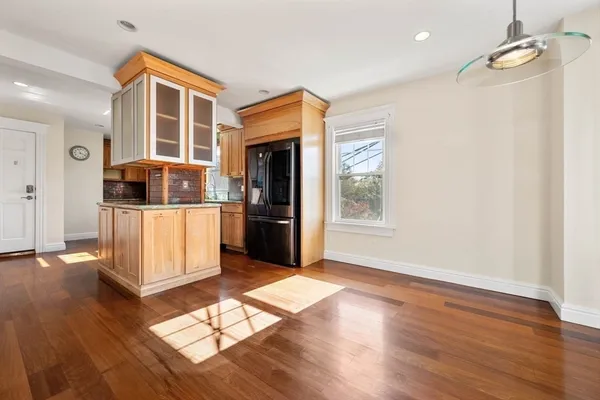 a living room with stainless steel appliances kitchen island granite countertop wooden floors and wide window
