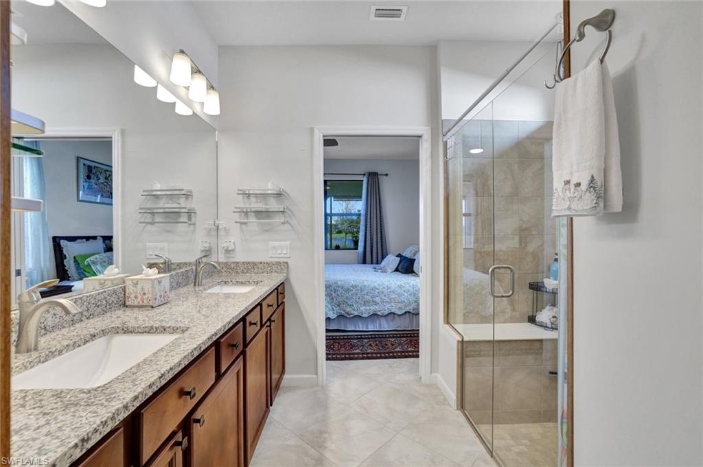 2171 Yellowfin Circle Naples, FL 34114 - Photo 15 of 38 a spacious bathroom with a granite countertop sink a mirror and shower