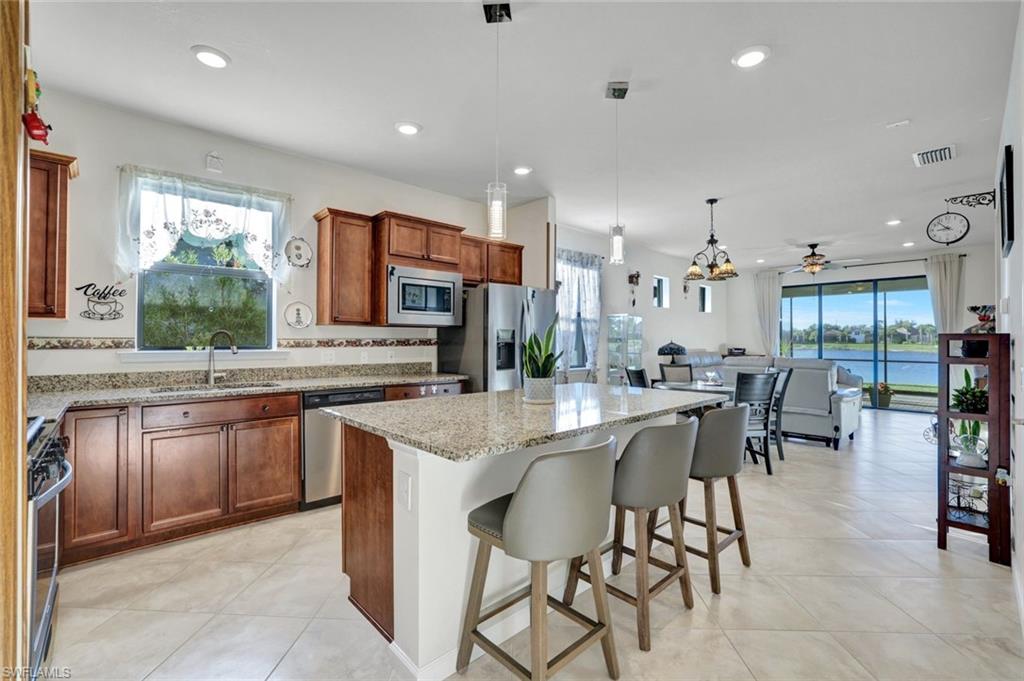 2171 Yellowfin Circle Naples, FL 34114 - Photo 6 of 38 a kitchen with stainless steel appliances granite countertop table chairs sink and cabinets