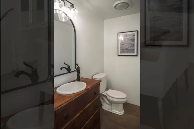 a bathroom with a granite countertop toilet sink and mirror