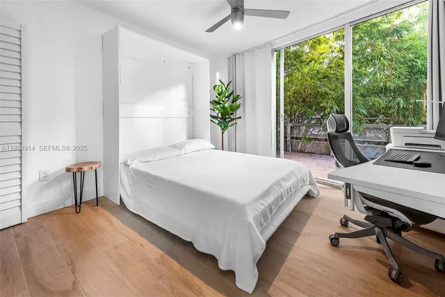 a bedroom with a bed a large window with table and chairs