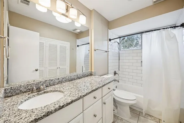 a bathroom with a granite countertop sink a toilet a mirror and shower