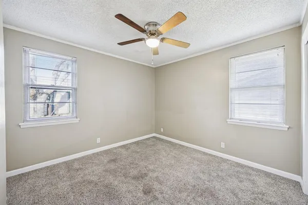 an empty room with windows and ceiling fan