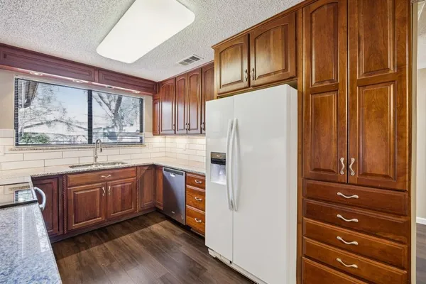 a kitchen with granite countertop stainless steel appliances a refrigerator cabinets and wooden floor