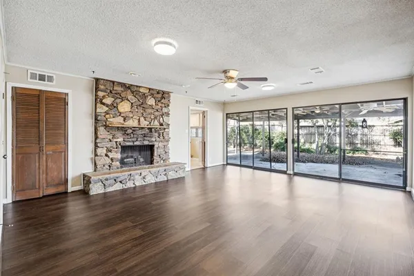 a view of an empty room with wooden floor and a fireplace