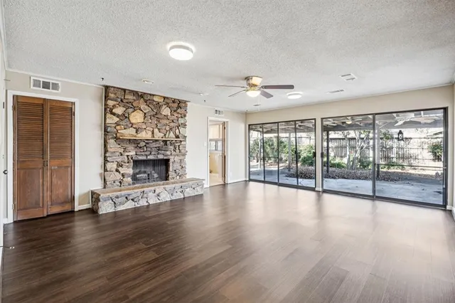 a view of an empty room with wooden floor and a fireplace