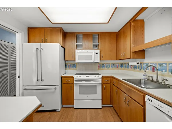 a kitchen with stainless steel appliances granite countertop a refrigerator a sink dishwasher and white cabinets with wooden floor