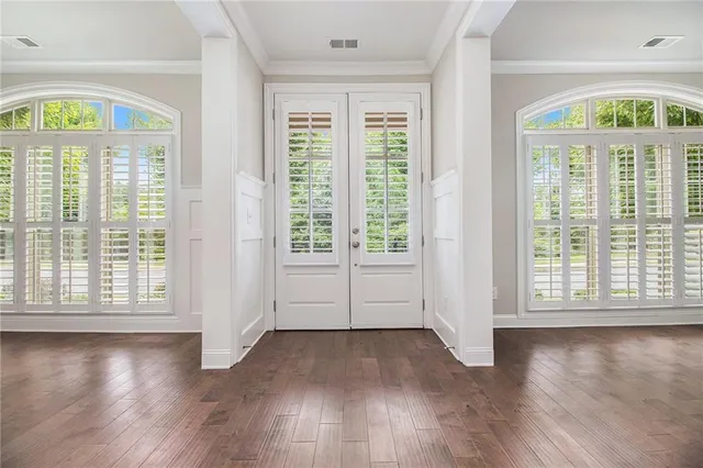 an empty room with wooden floor and windows