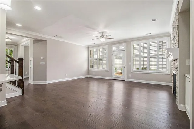 an empty room with wooden floor exposed radiator and windows