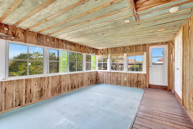 a view of an empty room with wooden floor and windows