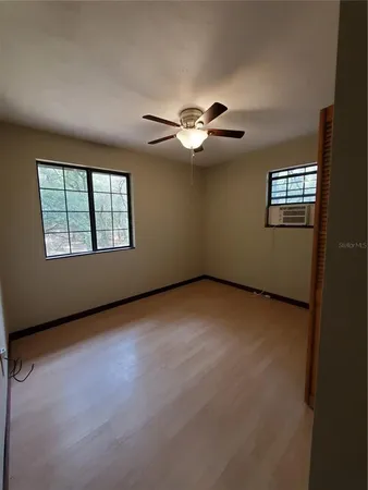 an empty room with windows and chandelier fan