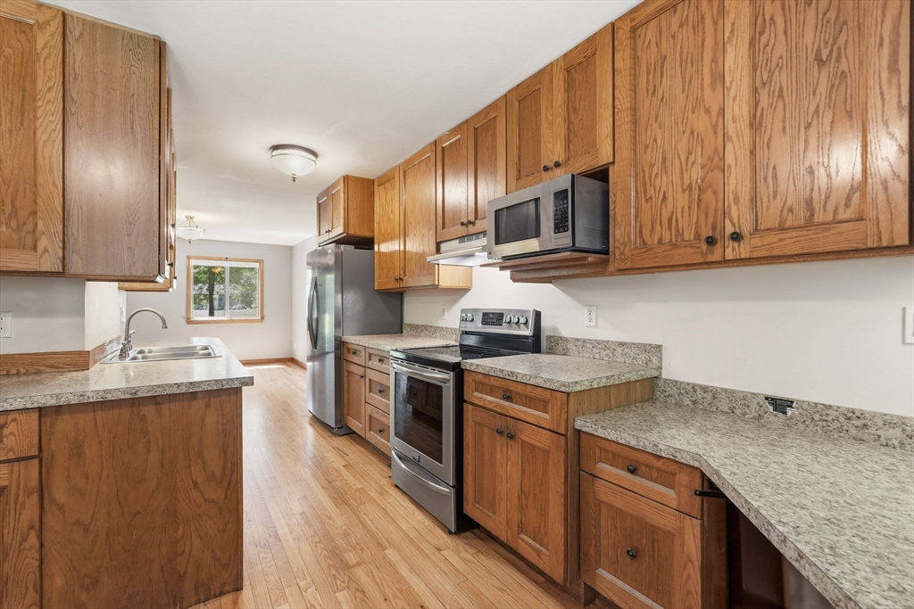 170 East Hadley Road, Unit 96 Amherst, MA 01002 - Photo 6 of 36 a kitchen with granite countertop wooden cabinets and a stainless steel appliances