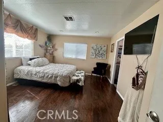 a bedroom with a bed a flat screen tv and a large window