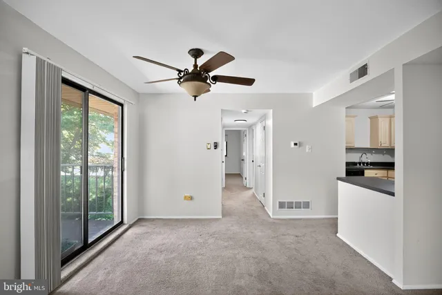 a view of a room with a ceiling fan and a kitchen view