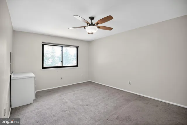 a view of an empty room with a ceiling fan and a window