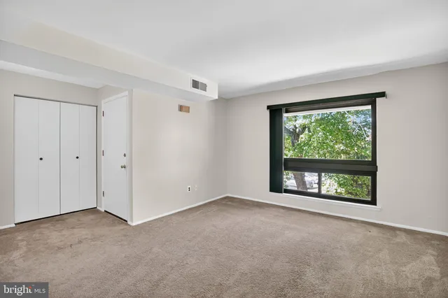 a view of an empty room with a window and kitchen view