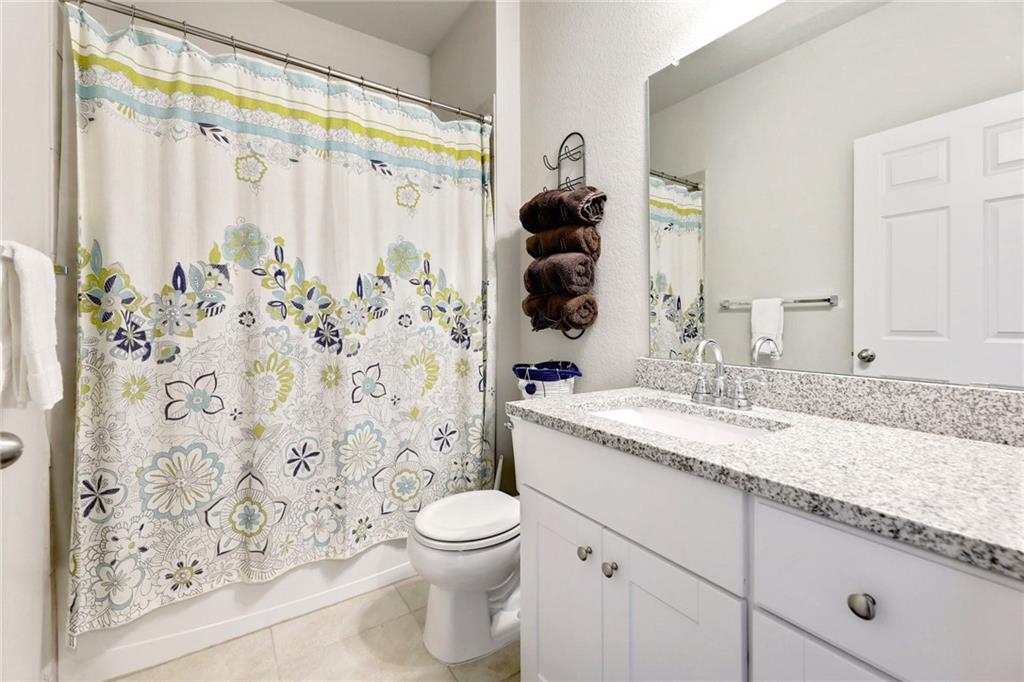 204 Tulum Terrace Leander, TX 78641 - Photo 7 of 22 a bathroom with a granite countertop sink a toilet and a shower curtain