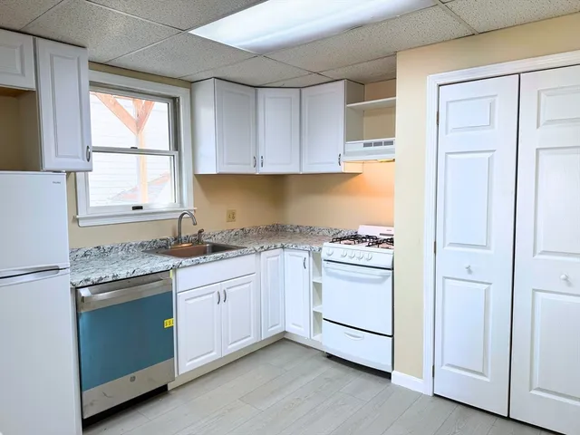 a kitchen with granite countertop white cabinets and white appliances