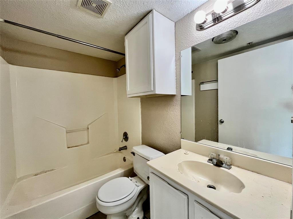 701 West Sycamore Street, Unit 104 Denton, TX 76201 - Photo 6 of 10 Clean, functional bathroom with a large vanity mirror, integrated sink, and classic tile surround.