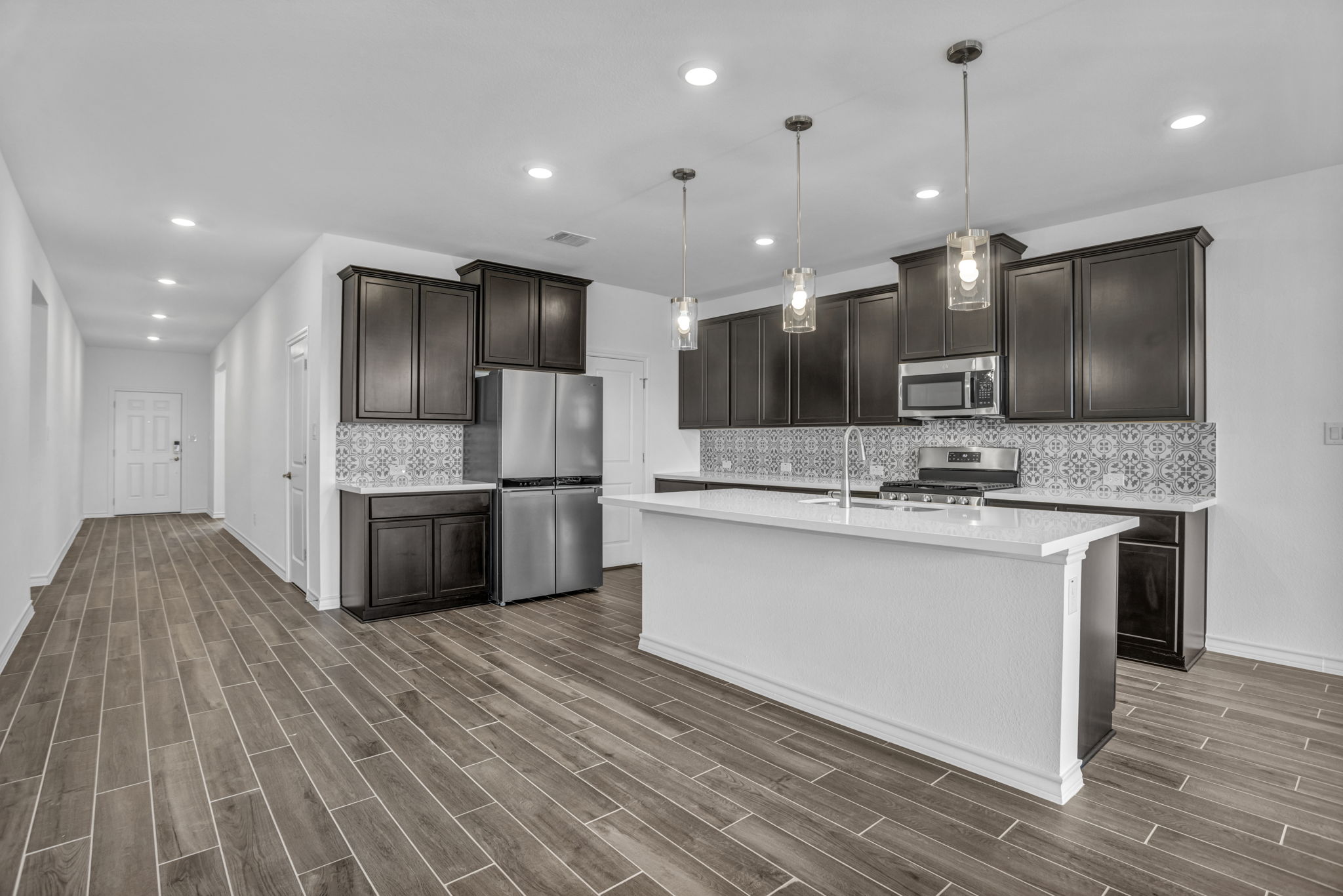 131 Adeline Road Hutto, TX 78634 - Photo 15 of 30 An open concept kitchen features an island, stainless steel appliances, and dark wood cabinetry.
