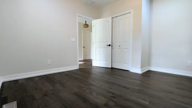 a view of an empty room with wooden floor and closet