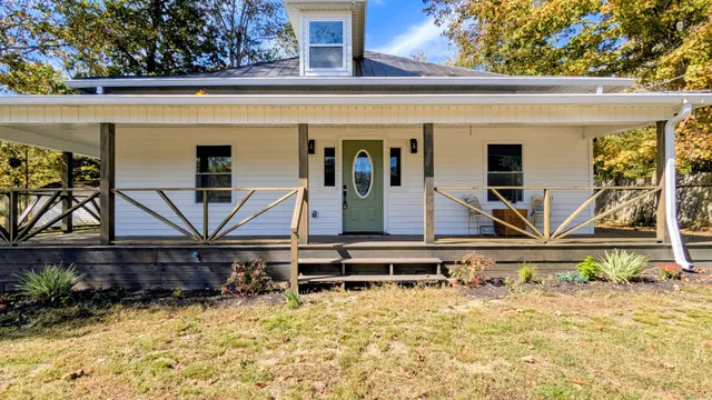 a view of house with wooden deck and furniture