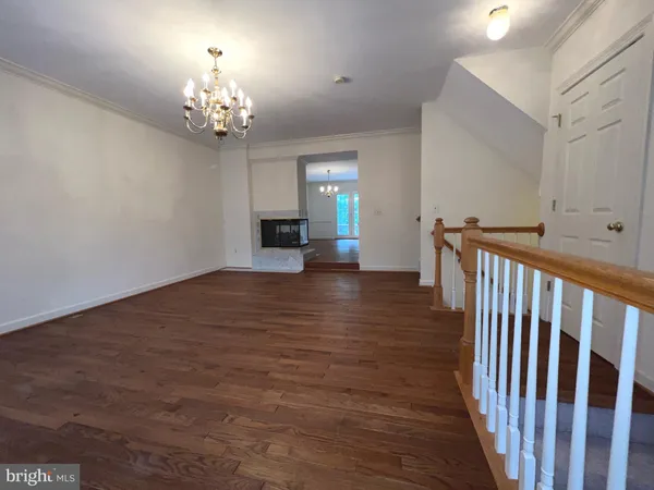 a view of a room with wooden floor chandelier and windows