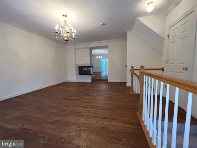 a view of a room with wooden floor chandelier and windows