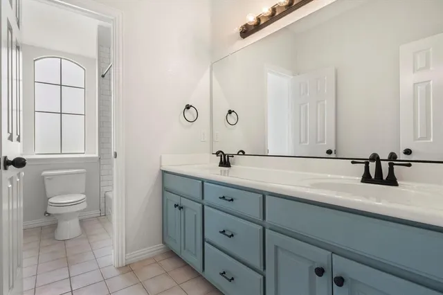 a bathroom with a double vanity sink toilet and a mirror