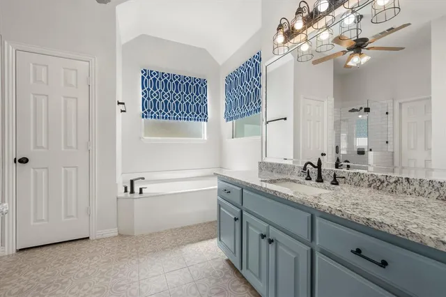 a bathroom with a granite countertop sink a large mirror and a bathtub