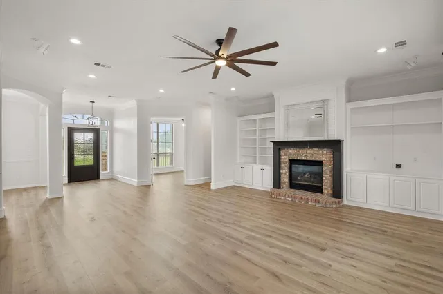 a view of an empty room with wooden floor and a fireplace