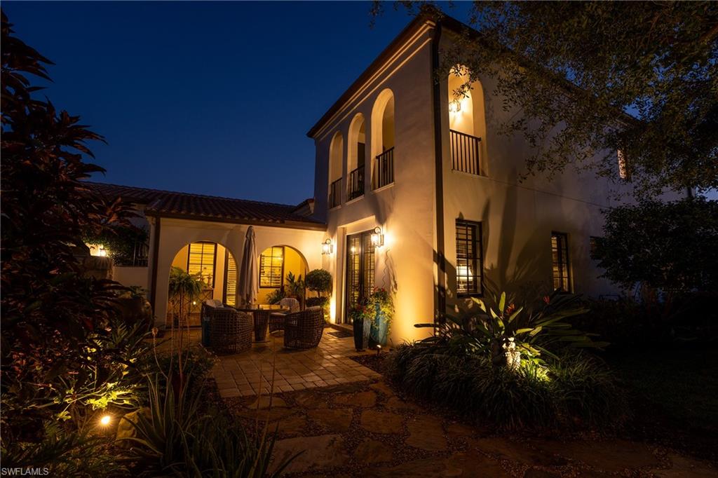 16727 Lucarno Way Naples, FL 34110 - Photo 43 of 48 Back of house at night with a tile roof, stucco siding, outdoor lounge area, a balcony, and a patio
