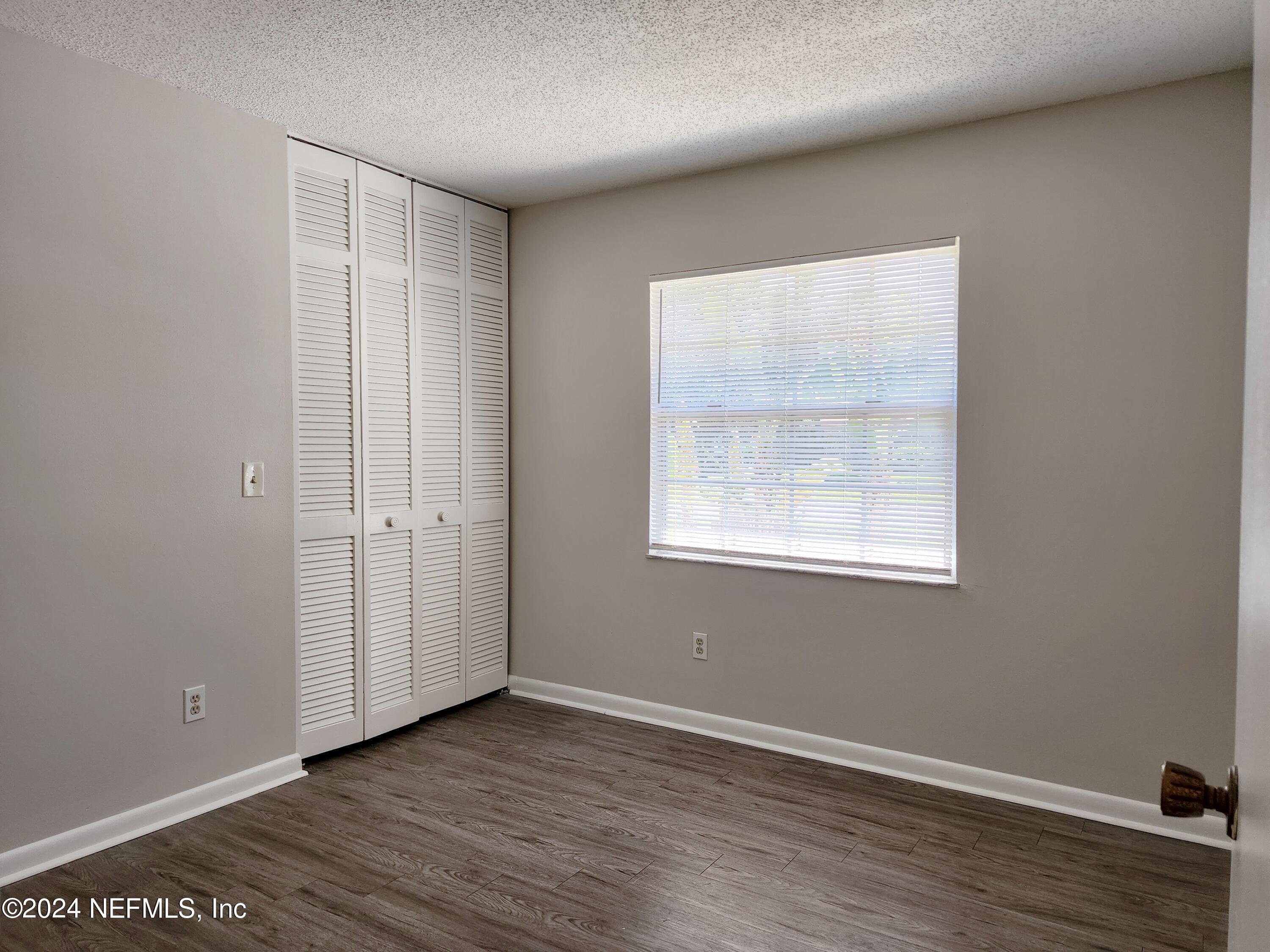 8423 Graybar Drive Jacksonville, FL 32221 - Photo 17 of 29 an empty room with wooden floor and windows