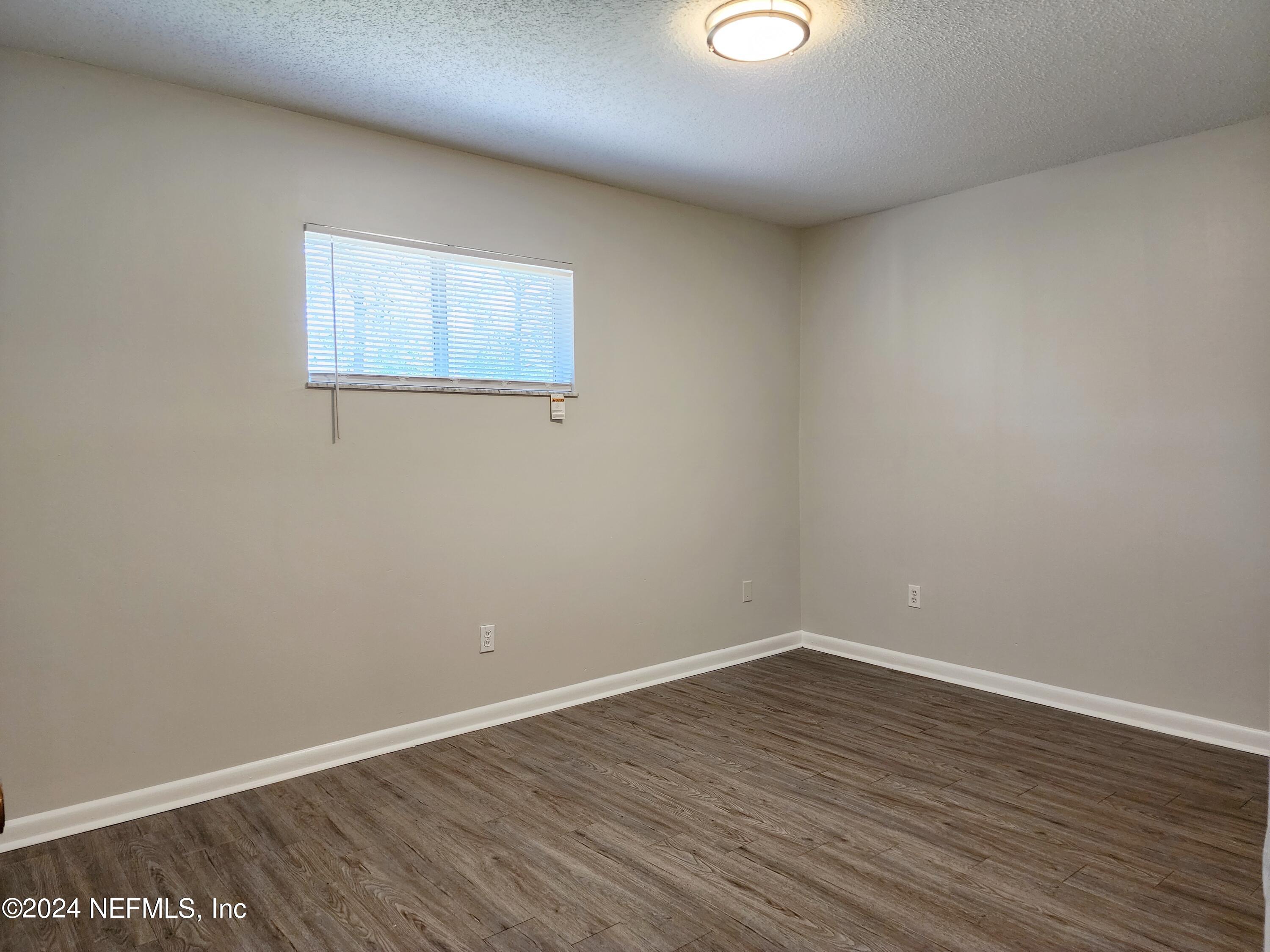 8423 Graybar Drive Jacksonville, FL 32221 - Photo 18 of 29 a view of an empty room with wooden floor and a window
