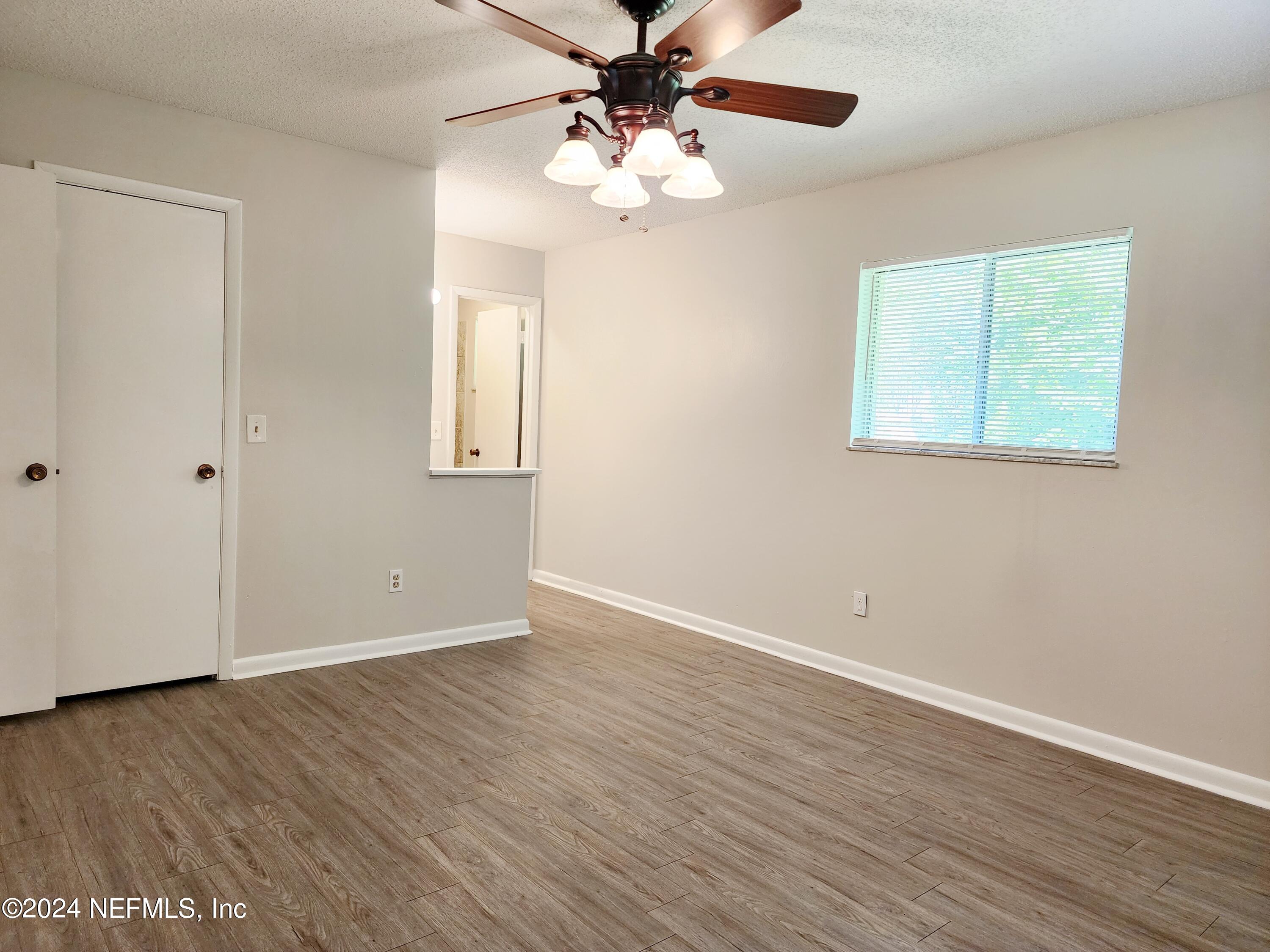 8423 Graybar Drive Jacksonville, FL 32221 - Photo 22 of 29 an empty room with wooden floor chandelier fan and windows