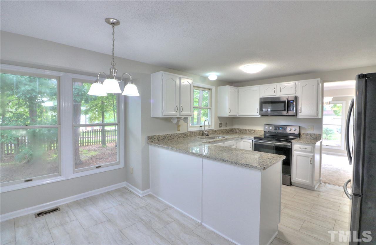 1909 Summerlyn Court Raleigh, NC 27609 - Photo 1 of 24 a kitchen with stainless steel appliances granite countertop a refrigerator a sink dishwasher a stove and white cabinets with wooden floor