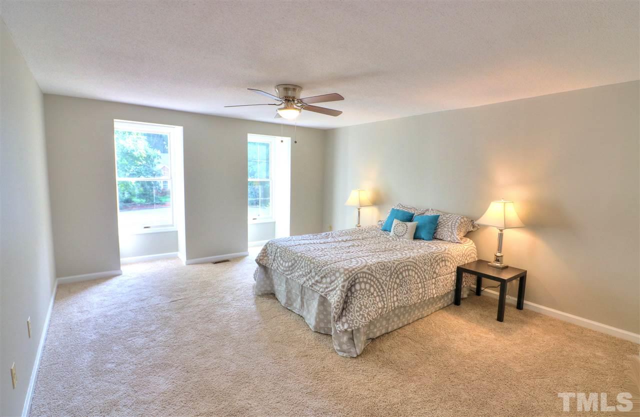 1909 Summerlyn Court Raleigh, NC 27609 - Photo 11 of 24 a spacious bedroom with a bed and a chandelier