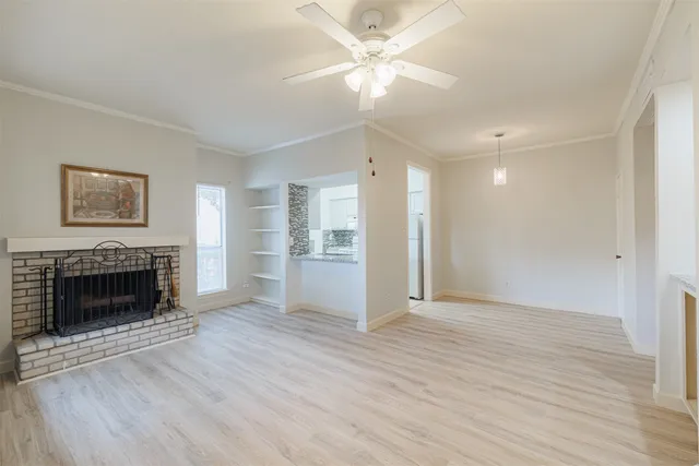 an empty room with wooden floor fireplace and windows